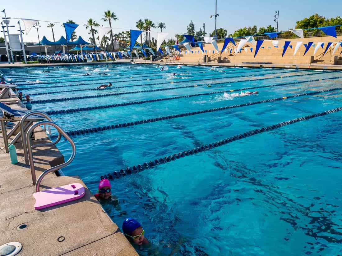 Outdoor swimming pool with active swimmers enjoying a sunny day under blue skies