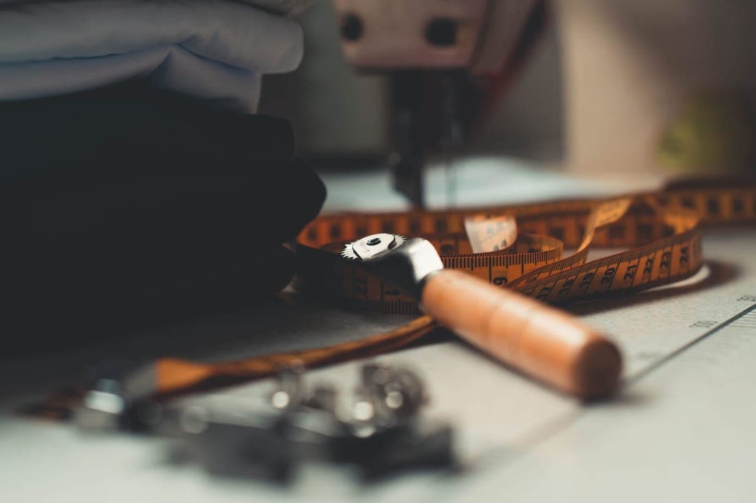 A detailed image of tailoring tools and fabrics on a workbench