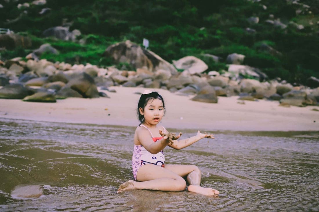 A cheerful child playing at the beach, enjoying the water and sand on a sunny day