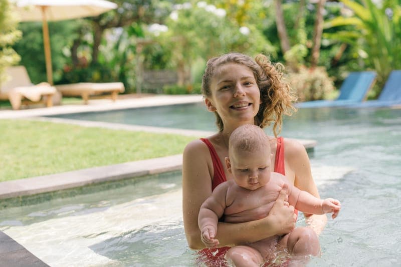 A smiling mother and her baby enjoying a sunny day in an outdoor pool