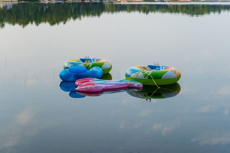 Three vibrant inflatable tubes resting on a serene lake, reflecting the peaceful water surface