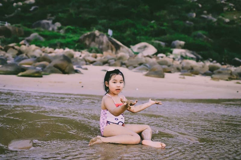 A cheerful child playing at the beach, enjoying the water and sand on a sunny day
